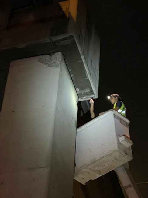 Tollway EQ damage — engineer inspecting bridge pier at night